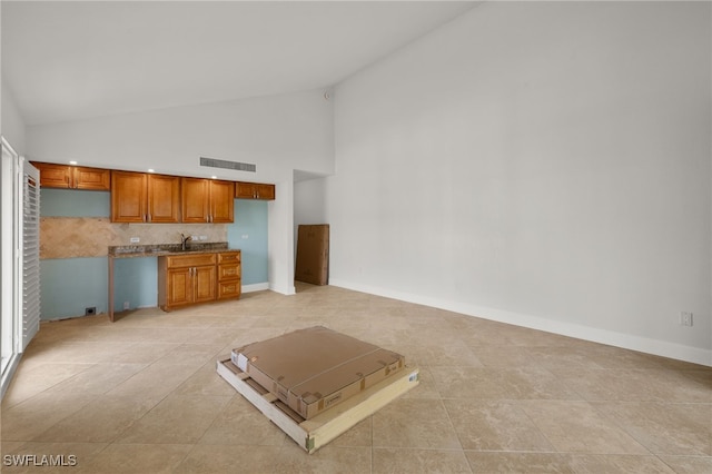 unfurnished living room featuring light tile patterned flooring, sink, and high vaulted ceiling