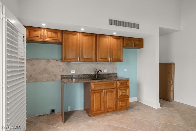 kitchen with dark stone counters, light tile patterned flooring, sink, and tasteful backsplash