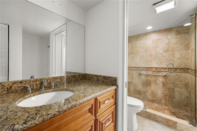 bathroom featuring vanity, toilet, a shower with door, and tile patterned floors