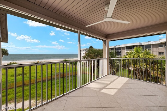 unfurnished sunroom with ceiling fan, a beach view, a water view, and a healthy amount of sunlight