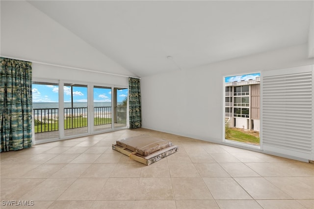 unfurnished living room featuring a water view, light tile patterned floors, and high vaulted ceiling