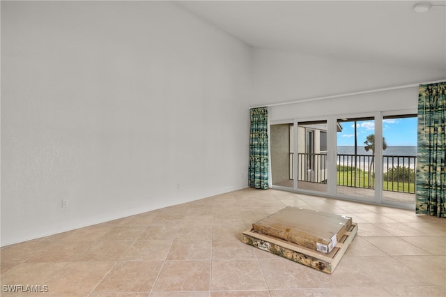 empty room with high vaulted ceiling and light tile patterned floors