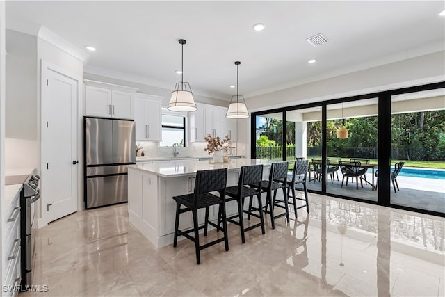 kitchen with white cabinets, decorative light fixtures, appliances with stainless steel finishes, and a center island