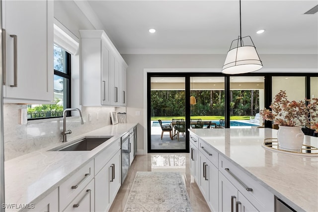 kitchen with white cabinets, sink, backsplash, light hardwood / wood-style flooring, and decorative light fixtures