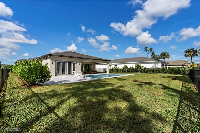 back of house featuring a lawn, a fenced in pool, a patio, and french doors