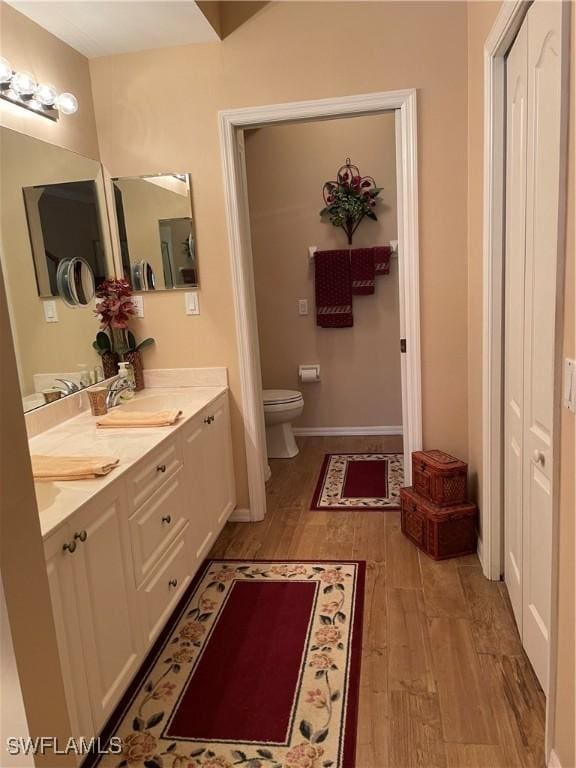 bathroom featuring wood-type flooring, toilet, and vanity