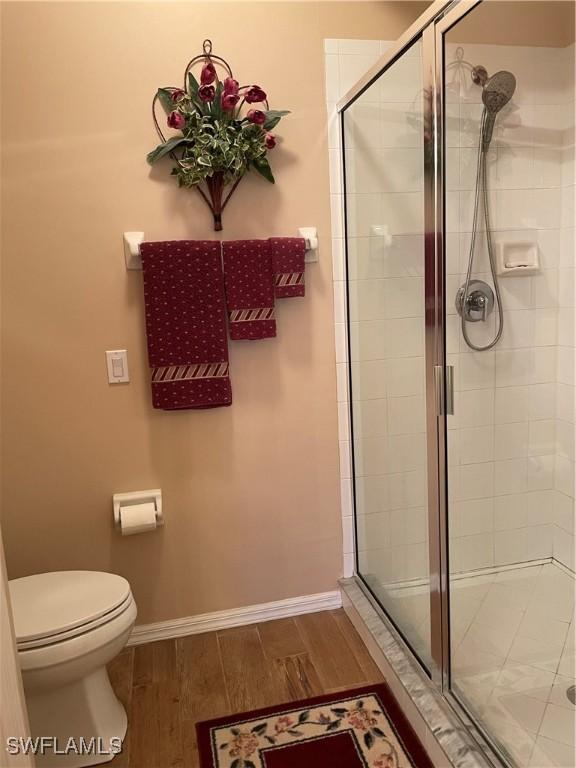 bathroom with hardwood / wood-style flooring, toilet, and walk in shower