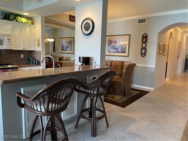 bar with white cabinetry, ornamental molding, light tile patterned flooring, and backsplash