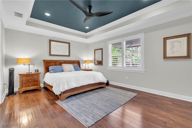 bedroom featuring ornamental molding, dark wood-type flooring, ceiling fan, and a tray ceiling