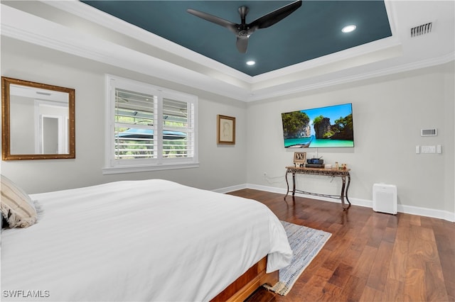 bedroom featuring ceiling fan, dark hardwood / wood-style floors, ornamental molding, and a tray ceiling