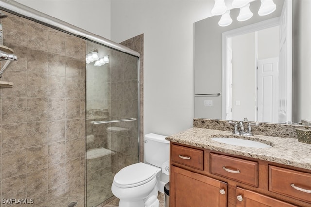 bathroom featuring vanity, toilet, and a shower with door