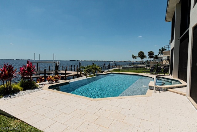 view of swimming pool featuring a dock, a patio area, a pool with connected hot tub, and a water view