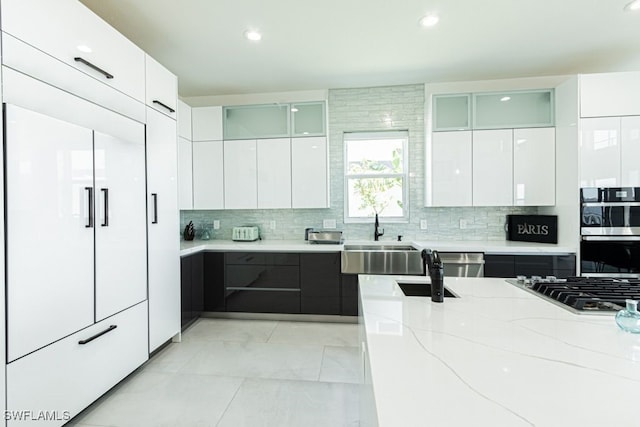 kitchen featuring tasteful backsplash, white cabinetry, a sink, and modern cabinets