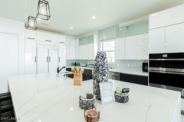 kitchen featuring modern cabinets, light stone counters, stainless steel appliances, and backsplash