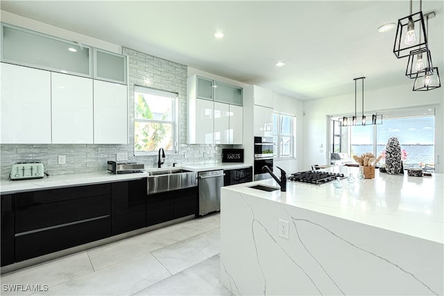 kitchen featuring tasteful backsplash, modern cabinets, appliances with stainless steel finishes, and a sink