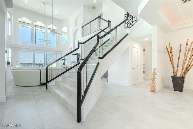 staircase featuring ornamental molding, visible vents, ceiling fan, and baseboards