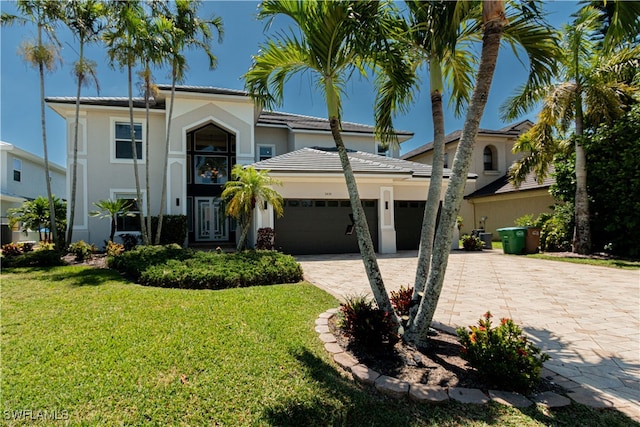 view of front of house featuring a front lawn, decorative driveway, an attached garage, and stucco siding