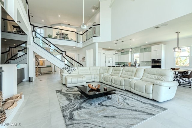 living area featuring an inviting chandelier, visible vents, a high ceiling, and stairway