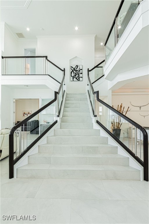 staircase with ornamental molding, recessed lighting, and a towering ceiling