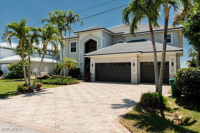 view of front facade with decorative driveway, an attached garage, and stucco siding