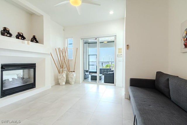 living room featuring a multi sided fireplace, a ceiling fan, and baseboards