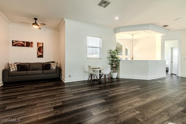 living area featuring dark wood-style flooring, a ceiling fan, visible vents, baseboards, and ornamental molding