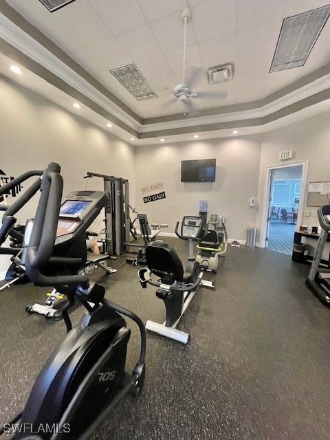 gym with a tray ceiling and ceiling fan