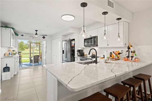 kitchen with hanging light fixtures, a breakfast bar, kitchen peninsula, and high quality fridge