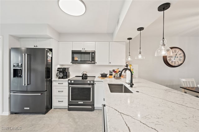 kitchen featuring pendant lighting, stainless steel appliances, sink, light stone countertops, and white cabinets