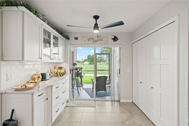 kitchen with backsplash, ceiling fan, light stone counters, white cabinets, and light tile patterned flooring