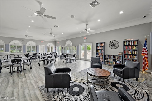 living room featuring ceiling fan, ornamental molding, light wood-type flooring, and french doors