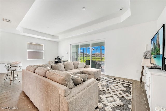 living room featuring a raised ceiling and light hardwood / wood-style floors