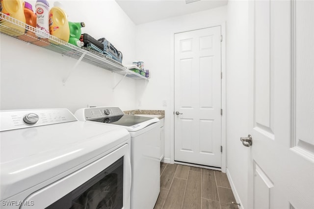 laundry area featuring washing machine and clothes dryer, dark hardwood / wood-style floors, and cabinets