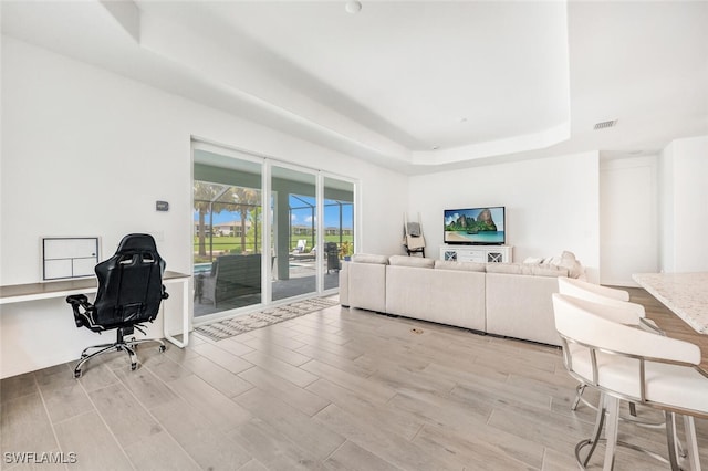 office space featuring a raised ceiling and light hardwood / wood-style flooring