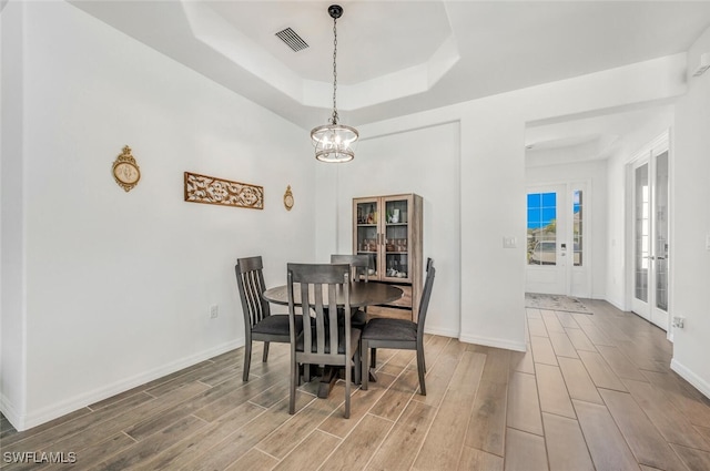 dining room featuring french doors, a notable chandelier, a tray ceiling, and hardwood / wood-style floors