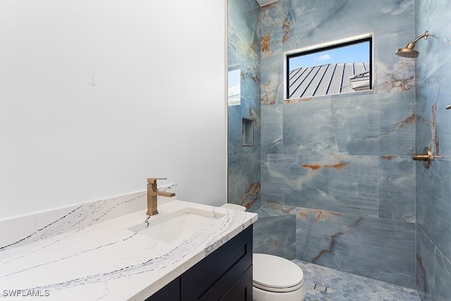 bathroom featuring vanity, toilet, and a tile shower