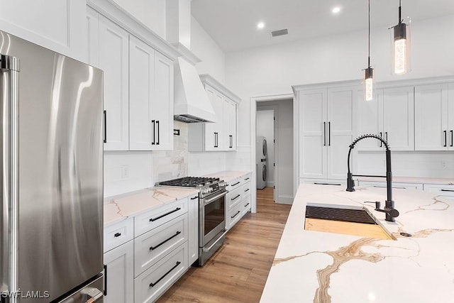 kitchen with white cabinetry, custom exhaust hood, pendant lighting, and high end appliances