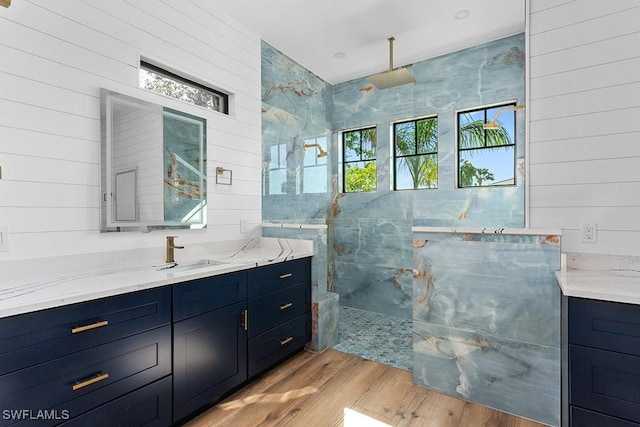 bathroom featuring tiled shower, wood-type flooring, and vanity