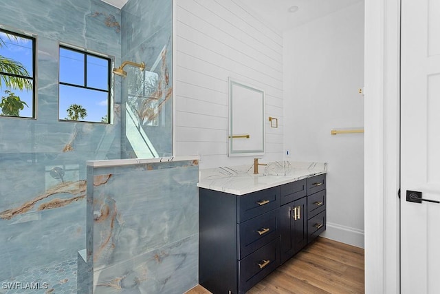 bathroom with hardwood / wood-style flooring, vanity, and a tile shower