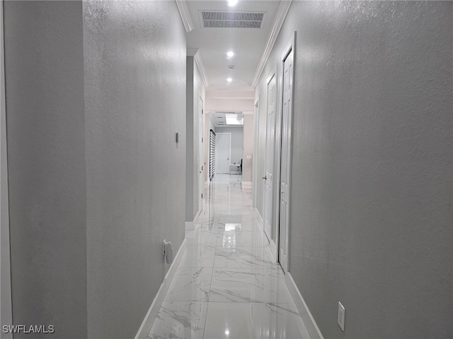 hall featuring marble finish floor, a textured wall, visible vents, and ornamental molding