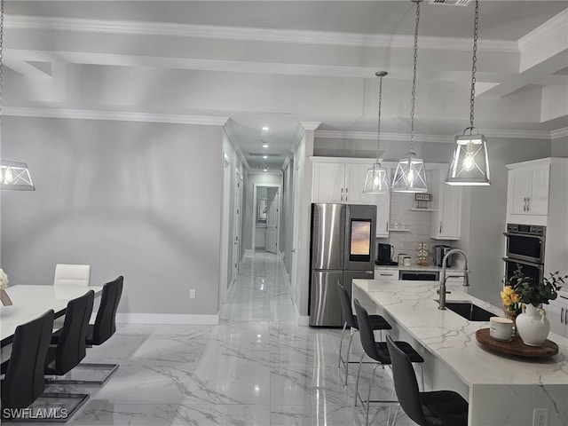 kitchen featuring white cabinets, appliances with stainless steel finishes, crown molding, a kitchen bar, and a sink