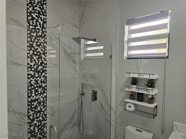 bathroom with toilet and a marble finish shower