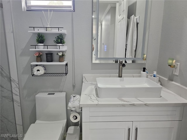 half bathroom featuring a textured wall, vanity, and toilet