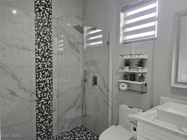 full bath featuring vanity, a marble finish shower, and toilet