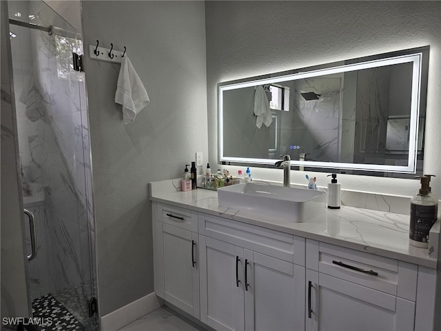 bathroom featuring marble finish floor, a marble finish shower, a textured wall, vanity, and baseboards