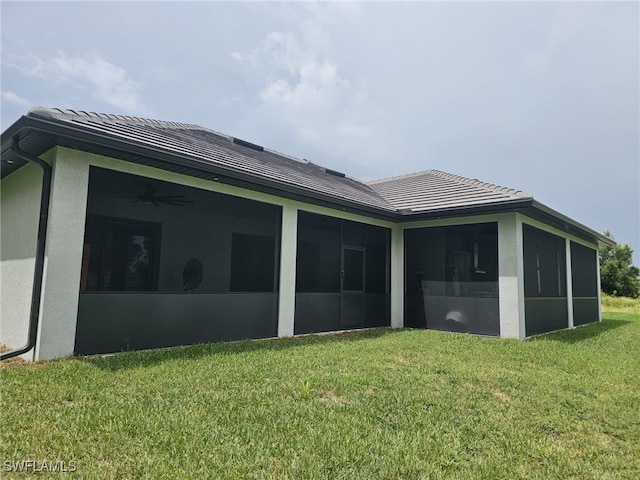 rear view of house with a yard, a sunroom, and stucco siding