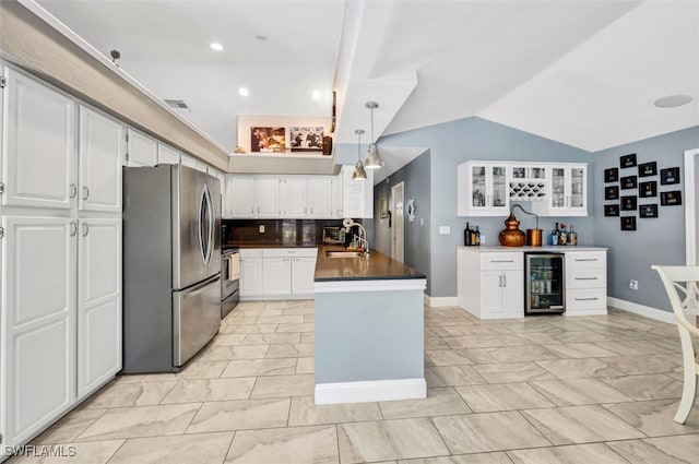 kitchen featuring lofted ceiling, stainless steel appliances, beverage cooler, and white cabinets