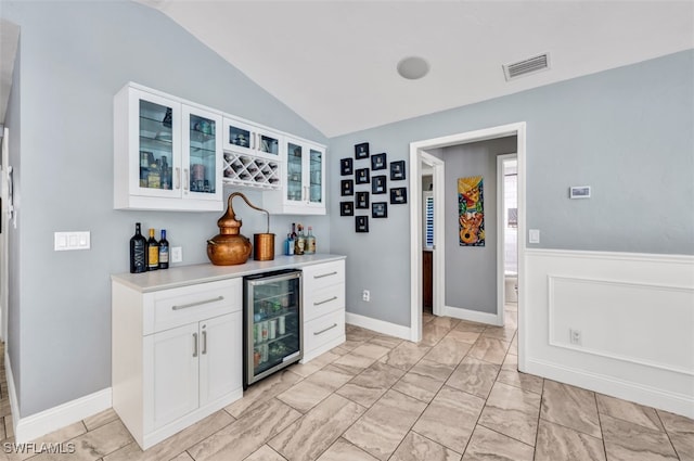 bar with vaulted ceiling, wine cooler, and white cabinets