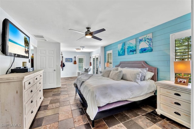 bedroom featuring ceiling fan and wooden walls