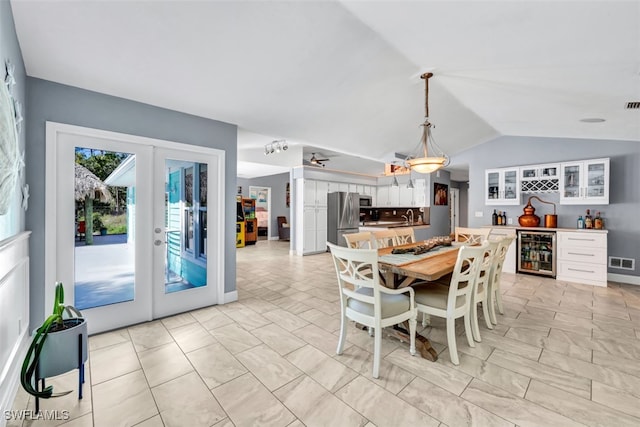 dining area with vaulted ceiling, beverage cooler, sink, and french doors